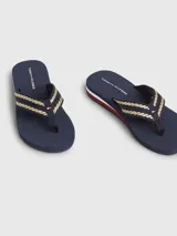 Ojotas Tommy Hilfiger color azul marino con tiras trenzadas en dorado y detalles distintivos de la marca.