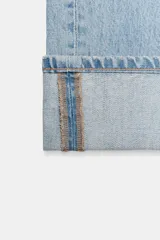 Jeans rectos de tiro medio en denim azul con efecto deslavado. Presentan diseño de cinco bolsillos, cierre frontal con botones metálicos y dobladillo vuelto en el bajo.