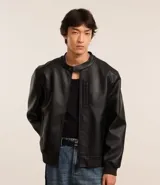 Campera negra de cuero sintético con cuello mao, cierre frontal con cremallera y bolsillo vertical con cremallera en el pecho.