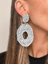 Aros colgantes artesanales de resina y metal plateado, con diseño texturizado en tonos celestes y plateados, adornados con bordes de strass.