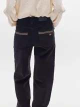 Pantalón de tiro medio confeccionado en pana negra, de corte holgado y diseño recto, con detalle de línea lateral en tono contrastante.