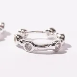 Par de aros tipo argolla plateados, con pequeños apliques circulares alrededor.