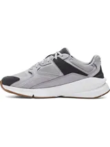 Championes Under Armour Forge 96 Reissue, con diseño inspirado en los años 90. Presentan una parte superior de malla gris con superposiciones de cuero nobuk y detalles en negro. Incluyen una entresuela blanca gruesa para mayor amortiguación y una suela exterior de goma color caramelo.