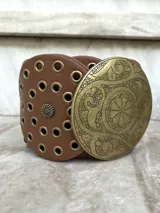 Cinto faja de cuero sintético negro con hebilla metálica dorada con diseño circular calado.