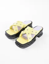 Sandalias amarillas con plataforma y tiras cruzadas con detalles de tachas.