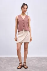 Chaleco de punto color crema con escote en V y cierre frontal con botones a tono.