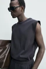 Camiseta sin mangas de corte relajado, confeccionada en tejido compacto de algodón con elasticidad, cuello redondo y diseño de sisa amplia.