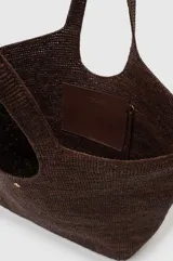Bolso tipo shopper extragrande de rafia tejida a mano en color marrón, con asas alargadas, silueta de estructura suave y detalle de llavero colgante de cuero sintético.