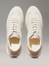 Zapatillas Calvin Klein de perfil bajo, confeccionadas en una combinación de ante, piel y lona en tonos beige. Presentan un diseño minimalista con suela de caucho y logo de la marca estampado en el lateral.