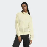 Campera deportiva Adidas Adicolor Sheer, color amarillo pálido, de corte holgado y tejido transparente. Cuenta con cierre frontal, cuello alto, puños y dobladillo acanalados, y las tres tiras características de la marca en las mangas.
