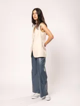 Chaleco color crema de lino con corte sastrero, largo a la cadera, forro interno, botones delanteros, silueta levemente entallada y tajo cruzado en la espalda.