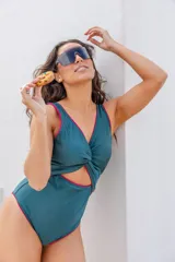 Malla enteriza de color verde inglés con detalles en fucsia, diseño con nudo frontal y abertura en la cintura.