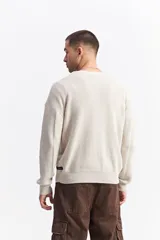 Sweater de algodón con textura acanalada, cuello redondo, mangas largas con hombros caídos y calce relajado. Presenta un logo bordado sutil en el pecho.