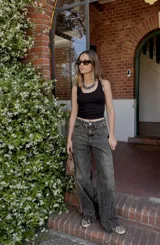 Pantalón jean azul oscuro, de corte wide leg y tiro medio. Presenta detalles de costuras diagonales en la parte superior.