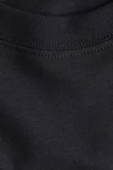 Remera de manga corta, cuello redondo y corte holgado, color gris oscuro o negro lavado, con estampado frontal en blanco que dice "CANNES 1980" y debajo "La Côte D'azur".