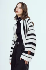 Cardigan de punto a rayas verticales blancas y negras, con mangas largas amplias y diseño abierto al frente.