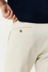 Pantalón chino de sarga elástica de algodón, con cierre de cremallera y botón, bolsillos laterales al bies y bolsillos traseros con botón. Presenta un corte ajustado que define la silueta.