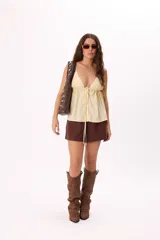 Top color amarillo pálido con breteles finos, escote en V profundo y ajuste frontal con botones.