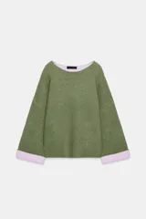 Jersey de punto de cuello redondo y manga larga con puños vueltos en contraste. Presenta un diseño holgado con aberturas laterales en el bajo.