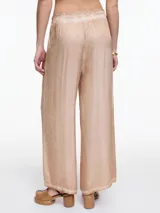 Pantalon de corte amplio y relajado, confeccionado en viscosa con acabado satinado y efecto lavado. Presenta cintura elastizada y detalles de desgaste en costuras y ruedo.