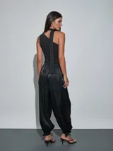 Pantalón negro de satén, de corte fluido y estilo bombacho, con cintura elástica y puños fruncidos en los tobillos con detalle de lazo.
