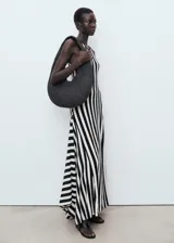 Vestido largo de punto fino con diseño a rayas verticales en blanco y negro, sin mangas, con cuello redondo y corte evasé.