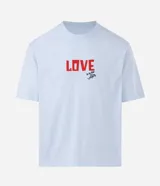 Remera boxy de algodón color celeste, con cuello redondo y mangas cortas. Presenta un estampado frontal con lettering y un estampado trasero grande con un corazón formado por círculos coloridos y una pequeña ilustración de una casa debajo, inspirado en la película "Up: Altas Aventuras".