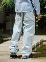 Pantalón de jean celeste lavado, de corte ancho y tiro alto con cordón ajustable en la cintura. Presenta detalles deshilachados en los bajos.