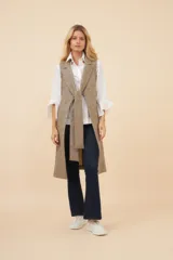 Chaleco largo color marrón claro, abierto, con lazo en la delantera y bolsillos ojal. Confeccionado en lana fina sin teñir.