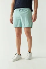 Short de baño liso de secado rápido, con cintura elástica ajustable mediante cordón, dos bolsillos laterales y uno trasero. Presenta un pequeño logo bordado en la parte inferior.