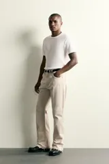 Jeans flare fit de tiro medio confeccionados en denim de algodón color beige, con cinco bolsillos, efecto salpicaduras y bajo irregular.