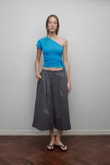 Bermuda gris de corte ancho, con pretina elástica, tiro bajo, bolsillos laterales y cierre lateral.