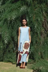 Vestido largo sin mangas de corte recto, color celeste con estampado floral grande en la parte inferior. Cuenta con cuello redondo y bolsillos laterales.