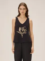 Musculosa de algodón color azul marino, con escote en V y un bordado artesanal de flor en el frente con contorno naranja y relleno dorado.