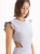 Vestido corto color gris de tejido satinado, con escote redondo, mangas con volados y aberturas laterales en la cintura. La falda es acampanada con doble volado en el ruedo.