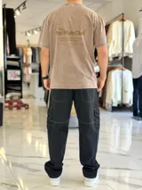 Remera oversize gris con efecto acid wash, de mangas cortas y cuello redondo, con estampado tipográfico blanco en la espalda.
