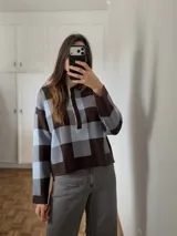 Sweater tejido de punto con diseño a cuadros grandes en tonos marrón y celeste, cuello polo con solapa de botones y mangas largas.