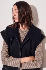 Chaleco negro con cuello de piel sintética, cierre frontal con cremallera y corte oversize.