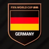 Buzo deportivo negro con cierre frontal parcial, cuello alto y mangas largas. Presenta detalles en rojo y naranja en los hombros, el logo de la FIFA World Cup 26 en el pecho y el escudo de Alemania.