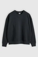 Buzo de cuello redondo con detalle de costura triangular en el escote, mangas largas con puños acanalados y dobladillo inferior elástico. Presenta un corte relajado y diseño minimalista.