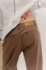 Pantalón de denim oscuro con tiro bajo y calce relajado. Presenta un cierre frontal con botones a la vista y costuras en contraste.