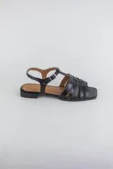 Sandalias de cuero color negro, de suela plana, con tiras entrelazadas en la capellada y tira ajustable en el talón con hebilla metálica.