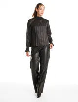 Blusa de satén negro con diseño de rayas verticales tono sobre tono. Presenta cuello alto con detalle de fruncido tipo smock, mangas largas con puños elásticos y terminación con volado.