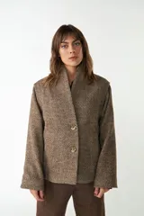 Chaqueta corta marrón con textura tweed, cuello alto, manga larga, forro al tono, bolsillos laterales y abrochadura delantera con dos botones.