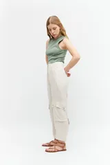 Pantalón de lino color beige melange, corte barrel, tiro alto, con bolsillos cargo laterales y cierre frontal.