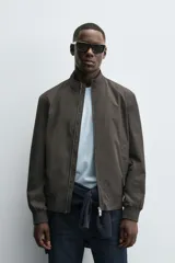 Cazadora de corte regular confeccionada en tejido técnico repelente al agua. Presenta cuello subido, manga larga con puños de rib, bolsillos laterales de vivo y cierre frontal con cremallera.