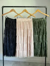 Maxi falda color beige con flecos escalonados y diseño de capas, confeccionada en tela elastizada con cintura elástica.