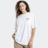 Remera blanca de corte oversized, con cuello redondo y mangas cortas. Presenta un pequeño estampado en el pecho con el logo de la marca Reef en color rojo y detalles de estrellas.