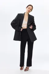 Leggings negros de punto pesado de corte sastre, con elástico oculto en la cintura, bolsillos decorativos en la parte trasera, pliegues cosidos al frente y pequeñas aberturas en los bajos.