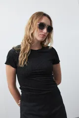 Top de manga corta color negro, confeccionado en terciopelo con textura acanalada y leve brillo. Tiene un calce ajustado y cuello redondo.